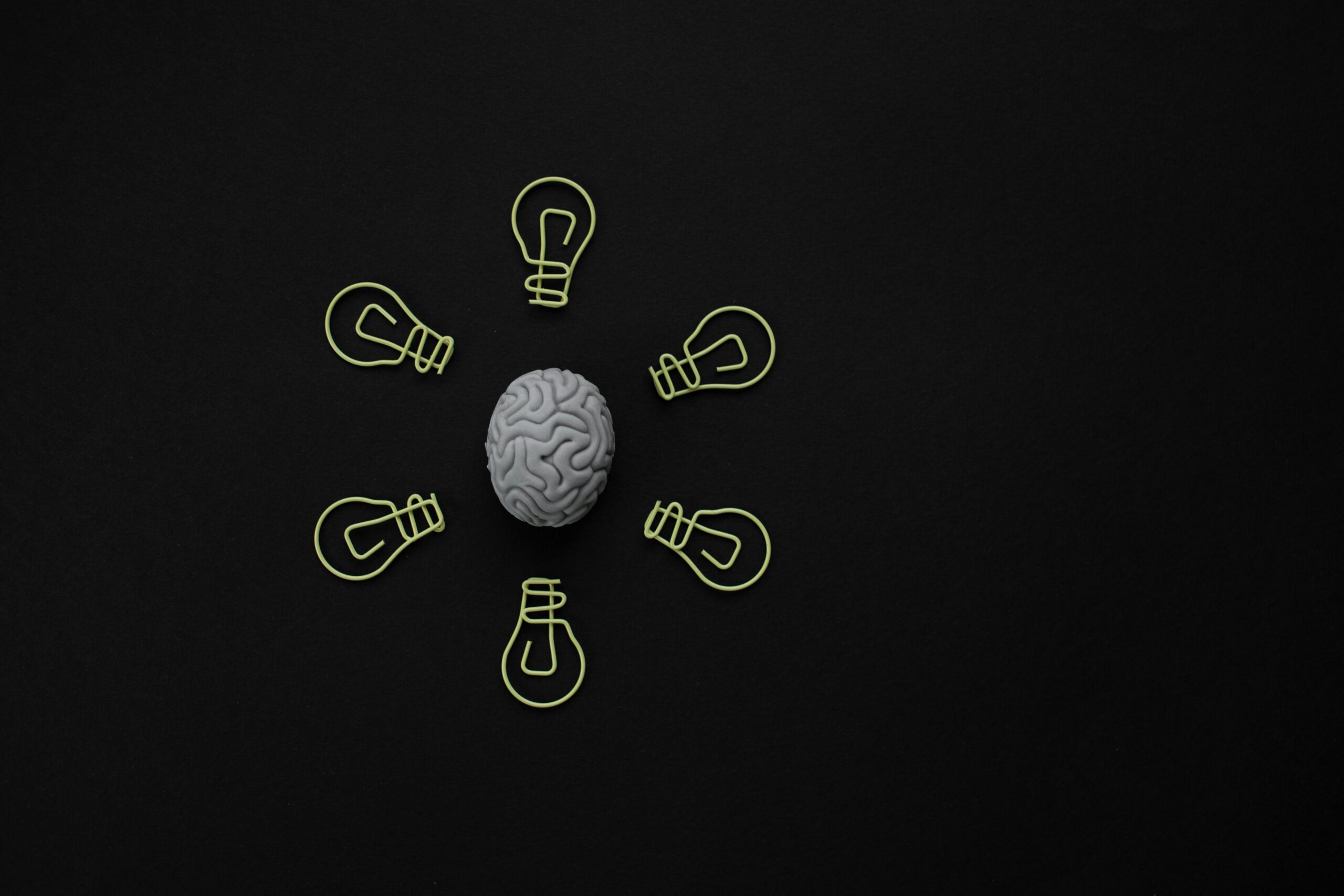 Conceptual photo of a brain surrounded by light bulb clips on black background.